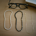 Three eyeglass chains: pearl, black and gold beaded, and fine gold link