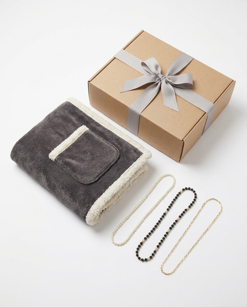 The Evening In set on white: the folded wrap with its pocket, three eyeglass chains, and the kraft gift box with a grey ribbon